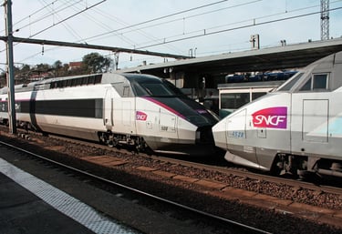 A high-speed TGV train stopped at a modern railway station platform