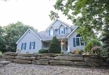 a house with blue horizontal siding, white windows and blue shutters