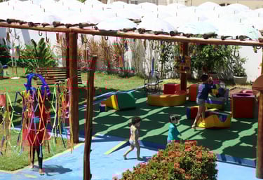 Espaço de brincadeiras com crianças brincando  com bola, e brinqueros acochoados