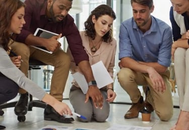 Diverse business team collaborating on floor with data charts and marketing reports.