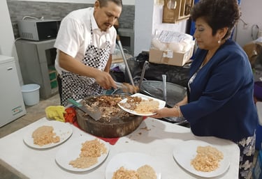 Cocinero sirviendo barbacoa en un evento, con platos de arroz y frijoles listos para los invitados.