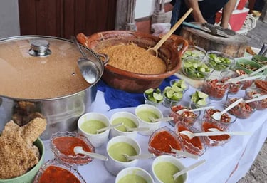 Mesa de servicio para evento con olla de frijoles, cazuela y salsas roja, limones y guarniciones