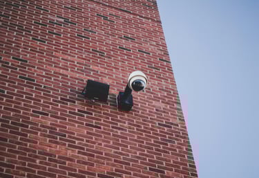 a camera mounted to a brick wall near a brick building