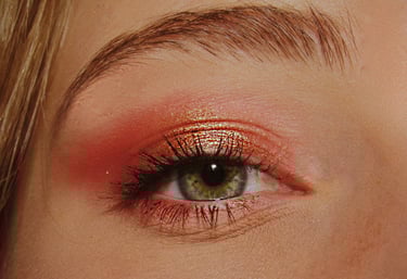 Une femme avec un maquillage des yeux rouge et un eyeliner doré.