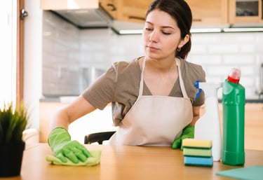 a woman in a apron and gloves cleaning a counter