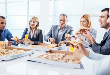 A group of coworkers eating a pizza lunch together. with some juice drinks.