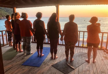A goup of women holding hands and looking out to sea as the sun sets in the Kabak Valley