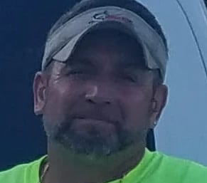 a man in a green shirt and a white hat