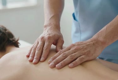 Close-up photography of professional physiotherapist hands performing a delicate technique on a patient's back. Calm and clinical atmosphere, soft daylight, palette of light blue and white, Southern European / Spanish clinic setting.