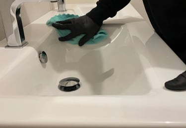 Nettoyage lavabo blanc. Mains avec gants noirs. Chiffon vert