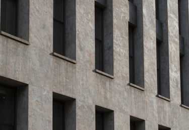 An abstract photography shot of architectural lines and shadows on a muted stone gray concrete wall in a North American / European city building.