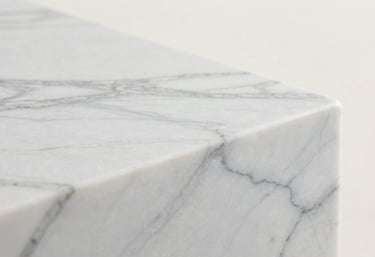 A close-up photograph of a polished white marble surface showing smooth, elegant grey patterns against a bright off-white background.