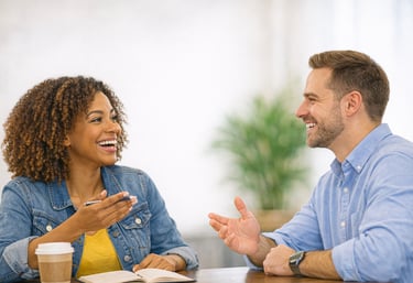 A diverse man and woman smiling and talking during a professional business meeting in a bright office