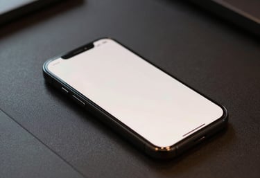 A close-up shot of a smartphone lying on a designer desk, with its screen glowing in a soft off-white light.