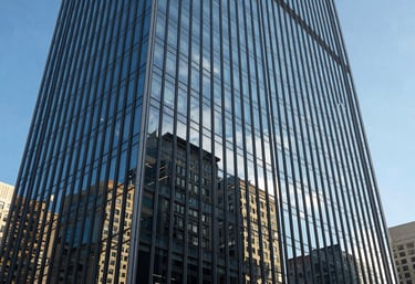 An architectural photography shot of a modern glass skyscraper reflecting a clear blue sky in a North American business district.