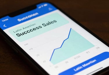 A close-up of a smartphone screen showing a successful sales graph with professional blue and soft mint colors in a Latin American / Spanish setting.