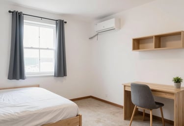 A neatly made single bed with soft pillows in a bright, shared bedroom.