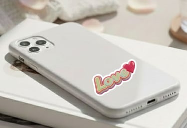 Close-up of a white smartphone with a "Love" heart sticker in a retro, vintage style.