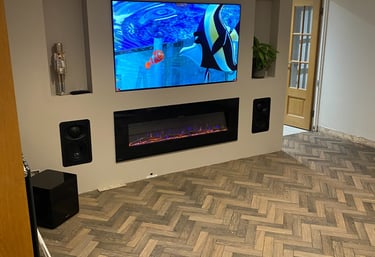 Living room with wooden floors and off white walls. A TV and fireplace are built into the wall.