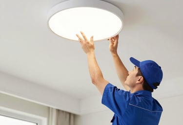 Electrician fixing a modern light fixture in a cozy São Paulo home with black and yellow tools.