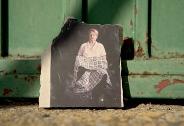 Vintage portrait of a seated woman holding a quilt, printed on a stone shard against a green door.
