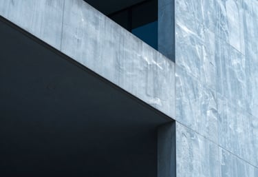 An artistic photograph of light and shadow on a modern architectural structure. The composition uses a cool palette of steel blue and pure ice, conveying stability and sophistication.