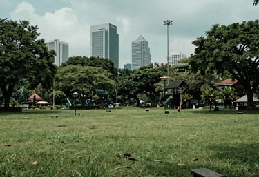A serene, clean park within a Southeast Asian / Indonesian city, representing the clean air resulting from waste-to-energy projects, soft teal and green tones.
