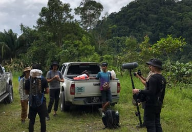 Jungle documentary filming team with local guides preparing equipment in Borneo rainforest Malaysia
