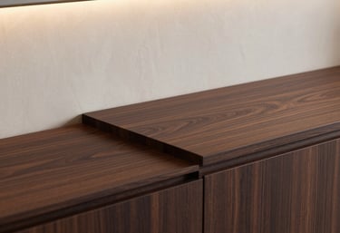 A close-up of luxury interior finishing details, featuring a dark espresso wood countertop and soft alabaster walls with sophisticated lighting.