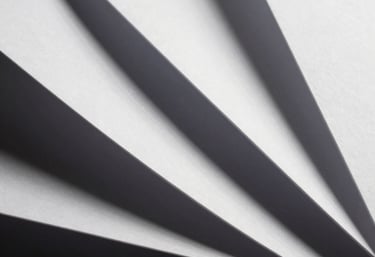 Abstract photography of white paper folds creating sharp geometric lines and deep shadows. Minimalist art style.