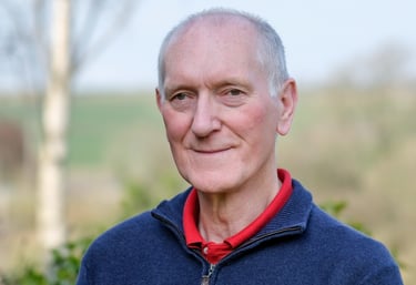 Portrait of white man with grey hair and blue jumper
