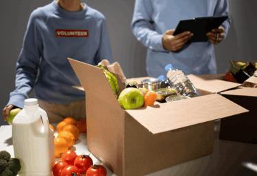Voluntarios llenando una caja de donaciones con productos y alimentos para un banco de alimentos