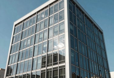 The exterior of a modern, finished corporate office building with a clean glass and steel facade, reflecting a bright blue sky, Latin American architecture.