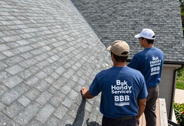 Professional roofing contractors from BGK Handy Services inspecting asphalt shingles on a residential roof.