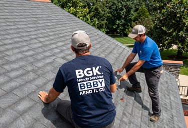 Professional roofing contractors from BGK Handy Services inspecting gray roof shingles for repair.