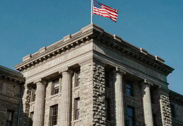 A low-angle shot of a distinguished stone foundation building with a North American flag, clear blue sky, majestic and permanent feel.