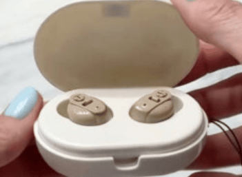 eine Person, die ein Paar Hörgeräte hält