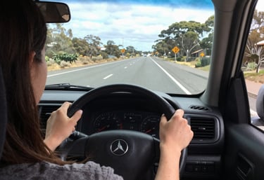 A warm, candid photo of a driving instructor calmly explaining dashboard controls to a student inside a car.