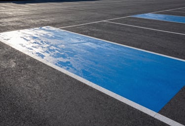 A pristine, dry commercial parking area with freshly painted steel blue markings and perfectly sealed surfaces.