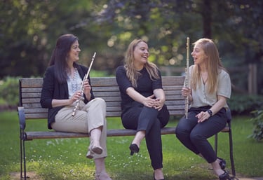 three women sitting on a bench in a park