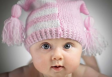 a baby girl wearing a pink hat with a pink and white hat