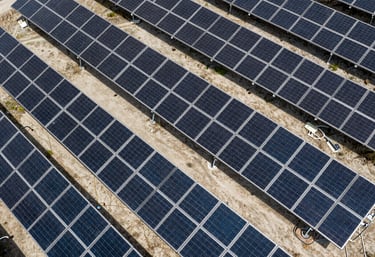 An aerial view of a solar farm or technical installation showing clean geometric rows, captured in shades of dark navy and light grey.