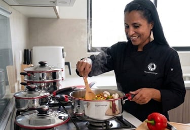 A smiling chef cooking fresh vegetables in Royal Prestige stainless steel cookware on a stove.