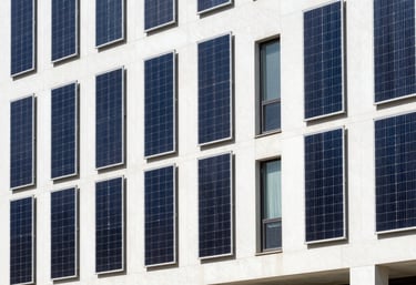 A bright, clean exterior shot of a modern commercial building in a Global Hispanic city, featuring vertical solar arrays integrated into the facade design. Daylight photography, professional style.