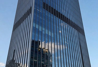 An abstract, professional view of a glass skyscraper in La Défense district reflecting a bright blue sky, symbolizing growth and high-level finance.