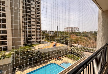 Technician installing a sturdy pigeon net on a Mumbai balcony under bright daylight.