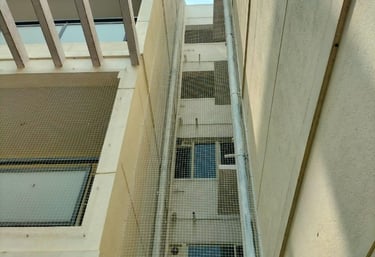Close-up of a sturdy pigeon net securely fitted on a balcony railing with a cityscape in the backgro