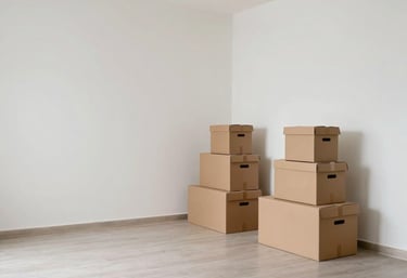 A photography shot of a wide, empty, and clean Indian luxury apartment living room with white walls, with neatly stacked boxes in one corner, signifying a successful and organized move.