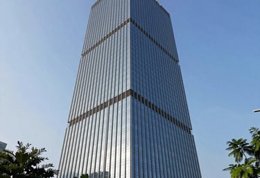 Architectural photography of a gleaming modern office tower in Jakarta, Indonesia, with large glass windows reflecting a clear blue sky, surrounded by greenery.