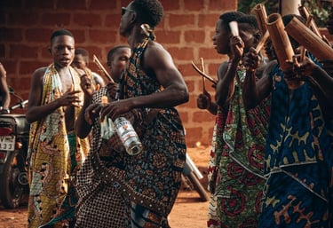 Groupe de femmes dans un village africain, dansant ensemble avec des mouvements rythmés et des sourires éclatants.